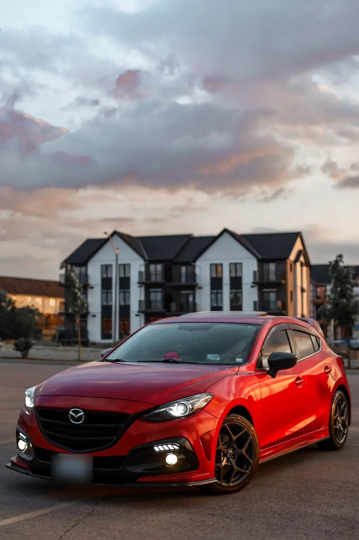 Mazda 3 màu đỏ trước dãy nhà